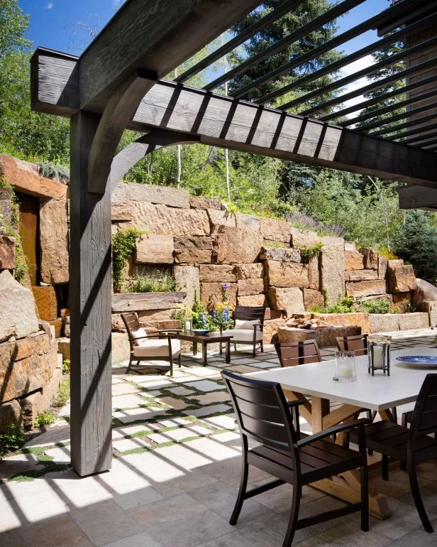 Patio with table and chairs beneath a wooden pergola, surrounded by greenery, showcasing a functional outdoor living space in Kernersville, NC.