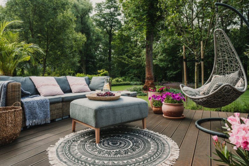 A cozy outdoor living space with a swing chair, decorative rug, and small table for backyard relaxation.