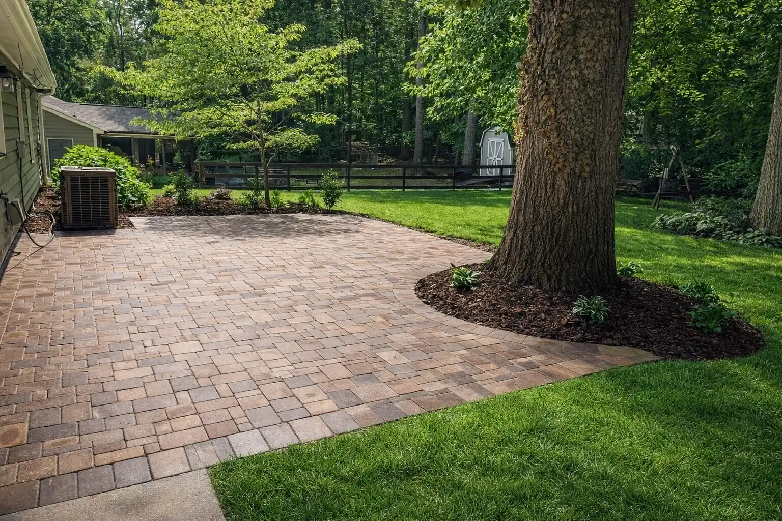 Brick patio surrounded by green lawn and a tree in a peaceful outdoor space